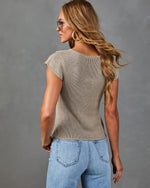 Woman wearing beige knit short sleeve sweater top and light wash high-rise jeans, back view, blonde hair