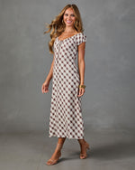 Woman wearing cream and mauve gingham plaid midi dress with cap sleeves, lace-up neckline, styled with strappy heels and gold bangles.