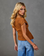 Woman wearing caramel ribbed knit off-shoulder sweater top with wide-leg blue jeans and gold earrings