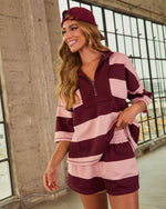 Woman wearing burgundy and pink striped quarter-zip pullover matching shorts set with coordinating burgundy bucket hat