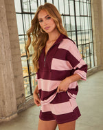 Woman wearing burgundy and pink striped oversized quarter-zip pullover top and matching shorts set