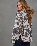 Woman modeling oversized cream and charcoal animal print denim shacket with dark jeans, back view