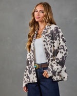 Woman wearing oversized cow print shacket open over white tank, dark jeans, turquoise concho belt, gold necklace