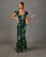 Green floral velvet burnout maxi dress with flutter sleeves, V-neckline and mermaid hem, styled with woven clutch and gold bangles