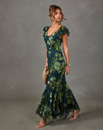 Green floral maxi dress with flutter sleeves, V-neckline and flowing mermaid hem, styled with gold cuffs and nude heels