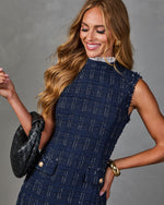 Woman in navy tweed sleeveless dress with gold buttons, lace collar, black woven bag, and gold accessories