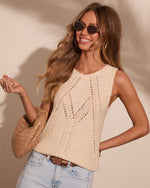 Woman wearing cream pointelle knit tank top with light wash jeans, tan woven bag, and round sunglasses, summer fashion