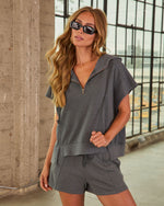 Woman wearing charcoal gray zip-up hooded short sleeve top and matching drawstring shorts two-piece set with sunglasses