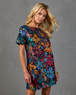 Woman wearing multicolor sequin floral mini shift dress with short sleeves on black background, festive party style