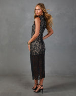 Black lace midi dress with nude lining, mock neck, sleeveless fit on model wearing strappy heels and gold bracelet