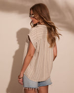 Woman wearing striped linen sleeveless shirt and denim cutoff shorts, back view, boho summer fashion lookbook