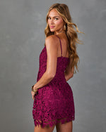 Woman wearing magenta floral crochet lace mini dress with spaghetti straps, open back, posing over shoulder