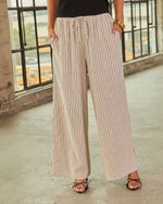 Wide-leg striped linen pants in cream and black with drawstring waist, styled with black strappy sandals and gold bangles