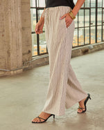 Wide-leg striped linen palazzo pants with drawstring waist, styled with black heels and gold bangles, worn by a woman