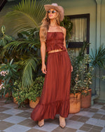 Rust boho two-piece crop top and maxi skirt set styled with tan cowboy hat, sunglasses, and ankle boots outdoors