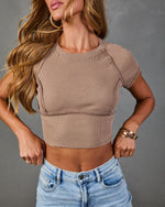 Women's ribbed taupe crop top with raglan sleeves and exposed seam detail, paired with light wash jeans