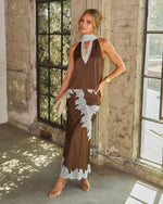 Woman in a brown satin lace-trim maxi skirt and halter top with sheer blue lace collar, styled with clear heels and a gold cuff