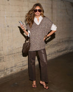 Woman in brown textured knit sweater vest over white shirt, coated brown wide-leg pants, strappy heels and woven saddle bag