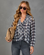 Women's navy plaid ruffle button-down blouse with long sleeves, styled with dark jeans and tan clutch bag
