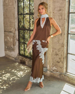 Woman in brown satin halter top and matching maxi skirt with pale blue lace trim, styled with clear heels and a clutch