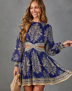 Navy blue and gold damask print boho mini dress with long sleeves, cutout waist, and flowy skirt on smiling woman