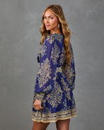 Navy blue and gold floral boho mini dress with long balloon sleeves, smocked cuffs, and ornate border hem on model