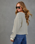 Woman wearing cream and navy striped ribbed long-sleeve top with blue jeans and aviator sunglasses, back view