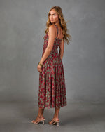 Woman in red floral midi dress with ruched bodice and full skirt, wearing clear heeled sandals and gold bangles, studio shot
