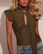 Olive green crinkle blouse with flutter sleeves, neck tie, keyhole neckline, and button front, styled with blue jeans