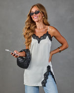 White satin cami top with black lace trim neckline and hem slit, styled with blue jeans and black woven bag