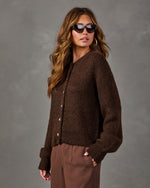 Woman in a chocolate brown knit button-front cardigan, cat-eye sunglasses and brown trousers, styled for fall fashion