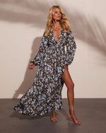 Olive green and blue floral maxi dress with deep V-neckline, billowy sleeves, and high slit, styled with strappy heels