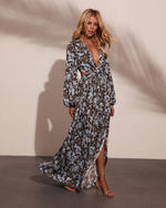 Floral maxi dress with deep V-neck, cutout waist, long sleeves, olive and blue print, worn with strappy heeled sandals
