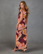 Woman modeling burgundy floral maxi dress with off-shoulder neckline, side slit, and clear heeled sandals