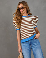 Woman wearing the Marcine Striped Puff Sleeve Top with horizontal stripes, puffed shoulders, and blue trims, styled with jeans and accessories for a chic look.