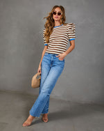 Model wearing the Marcine Striped Puff Sleeve Top with puffed shoulders, styled with high-waisted jeans and accessories, showcasing a chic spring/summer look.