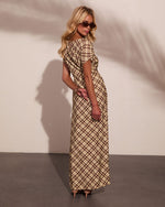 Woman in cream and brown plaid maxi dress with flutter sleeves, kitten heels, and oval sunglasses, posed from behind
