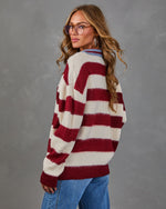 Woman in oversized burgundy and cream striped fuzzy knit sweater with blue collar, styled with wide-leg jeans and glasses