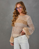 Woman in a chunky neutral ombré knit sweater with bell sleeves, white jeans, and tortoiseshell blue-light glasses