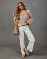 Woman in tan striped knit sweater, white wide-leg jeans, brown belt, suede tote bag and platform slip-on shoes
