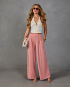 Woman wearing pink wide-leg palazzo pants with white ribbed halter crop top, gold accessories, and strappy sandals