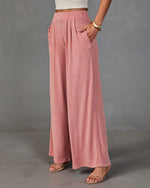 Dusty rose wide-leg palazzo pants with pleated high waist and side pockets, styled with strappy sandals