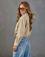 Woman wearing khaki cropped button-up shirt tucked into light wash wide-leg jeans, styled with aviator sunglasses and hoop earrings