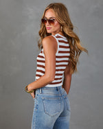 Woman wearing brown and white striped sleeveless crop top with light wash skinny jeans, gold accessories, and aviator sunglasses