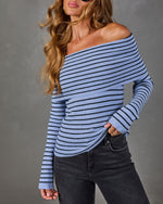 Blue and black striped off-the-shoulder foldover sweater with long sleeves, styled with high-waisted dark gray jeans