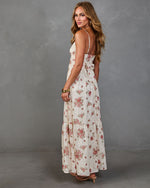 Woman modeling cream floral maxi dress with pink roses, tiered skirt, open back bow detail, and thin straps