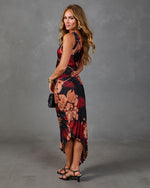 Woman modeling sleeveless floral print pleated high-low midi dress in burgundy black with strappy heels and mini bag