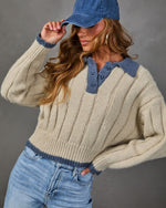 Cream ribbed knit polo sweater with blue collar and trim, styled with light wash jeans and a blue denim baseball cap