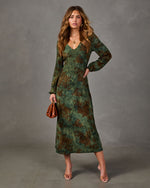 Green floral midi dress with long sleeves and V-neckline, styled with clear heels and a brown leather clutch