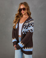 Brown Fair Isle cardigan with blue and cream pattern, worn open over a white crop top, light wash jeans and sunglasses